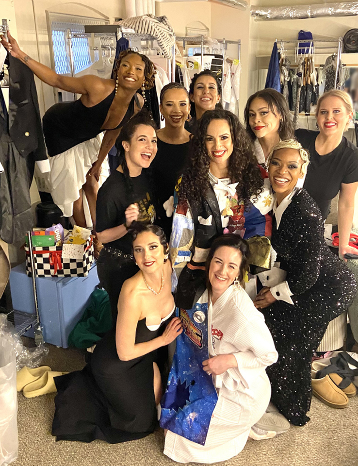 Lafarga poses in the Robe in a dressing room, surrounded by nine other female presenting people.