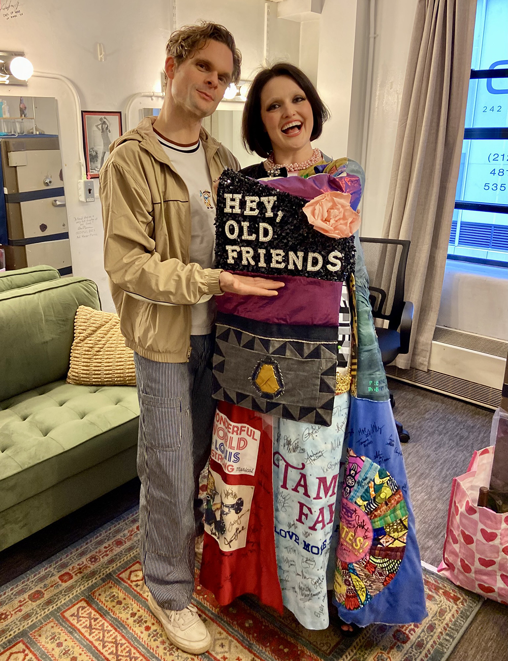 Reilly stands in a dressing room with Andrew Durand. She holds up her arm to highlight a panel of the Robe's sleeve that reads 