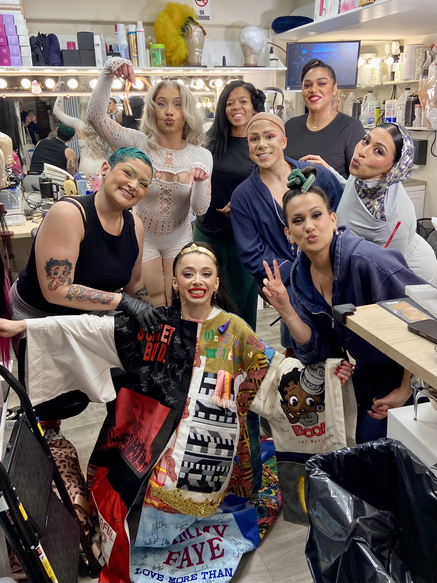 Emma Sofia poses in the Robe in a dressing room surrounded by seven other people.