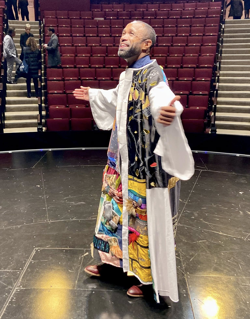 Alan Wiggins stands onstage in the Robe with his arms out, house seats visible behind him.